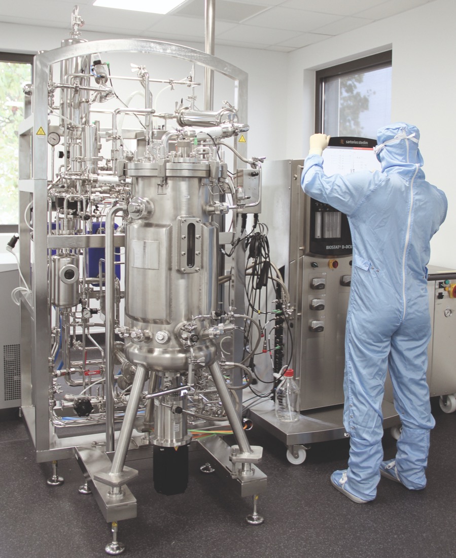 A researcher in protective coveralls operating a bioreactor at the Bio3 Institute